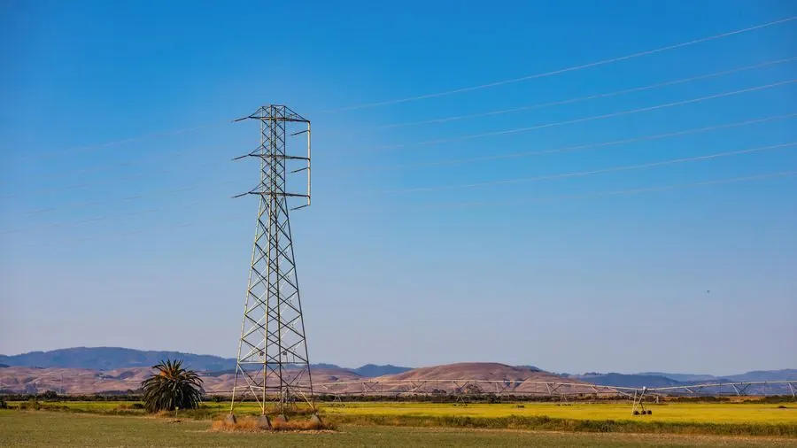 Pojedynczy słup energetyczny na trawiastym polu pod czystym błękitnym niebem